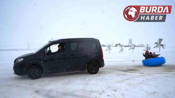 Aracının arkasına bağladığı şambrel ile çocuklara kayak keyfi yaşattı